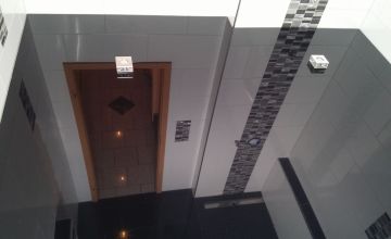 Dunkle Lackspanndecke mit Mosaik-Streifen und Designer-Spot im Badezimmer – Beispiel für Spanndecken in Olpe und Umgebung
